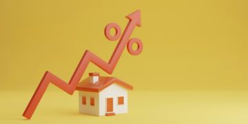 A small model house stands on a yellow background with an orange zigzag line and percentage symbol, ending in an upward-pointing arrow, to indicate rising interest rates or housing market trends, suggesting the need for the best fixed-rate mortgage. | TraceLoans