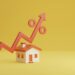 A small model house stands on a yellow background with an orange zigzag line and percentage symbol, ending in an upward-pointing arrow, to indicate rising interest rates or housing market trends, suggesting the need for the best fixed-rate mortgage. | TraceLoans